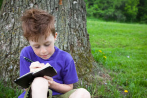 Happy Child Writing in a Journal Outside
