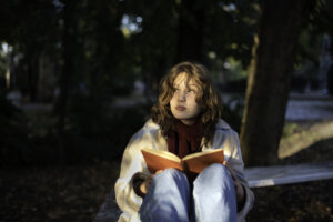 Portrait of a teenage girl reading a book in a city park